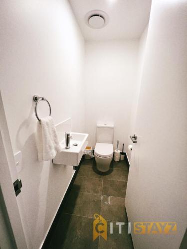 a white bathroom with a toilet and a sink at Contemporary in Kingston-2bd Apt in Kingston 