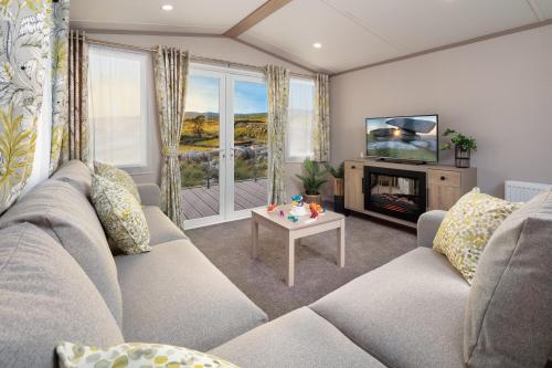 a living room with a couch and a television at Honeysuckle Prestige Holiday Homes in Chapel Saint Leonards