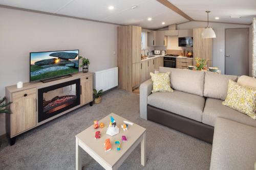 a living room with a couch and a tv and a table at Honeysuckle Prestige Holiday Homes in Chapel Saint Leonards