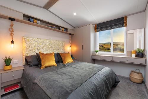 a bedroom with a large bed and a window at Honeysuckle Prestige Holiday Homes in Chapel Saint Leonards
