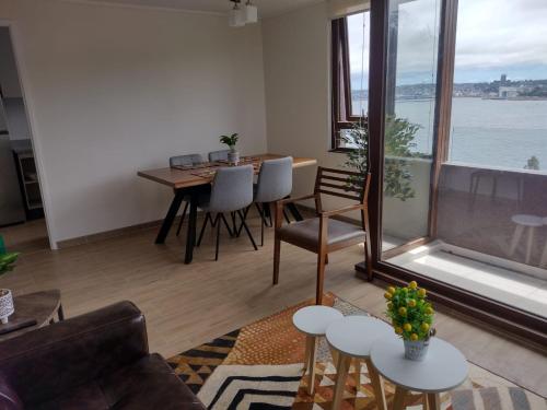 a living room with a table and chairs and a large window at Departamentos Terramar in Puerto Montt