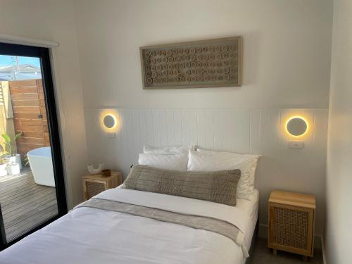 a bedroom with a bed with white sheets and a window at 4BR Waterfront - Skippers Quarterdeck in Lakes Entrance