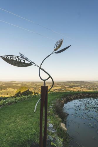 a metal bird sculpture on a hill next to a river at Mt Hay Retreat in Berry