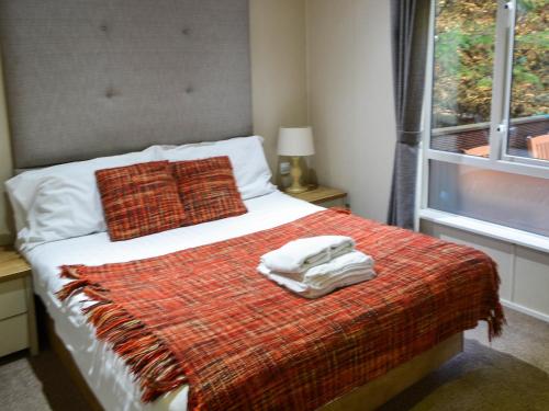 a bed with a red blanket and two towels on it at Griffon Lodge - Uk3469 in Felton