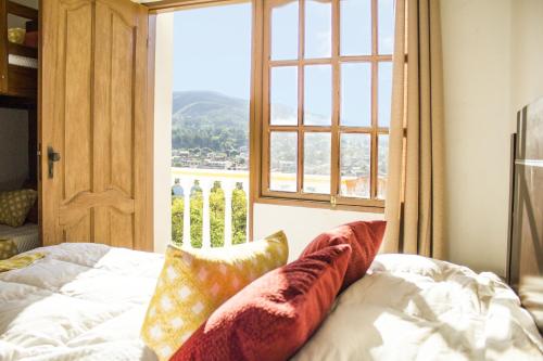 a bed with pillows on it in a room with a window at Colina Verde in Samaipata