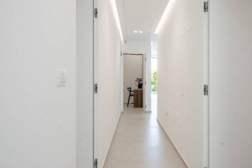 a hallway with white walls and white floors and a door at Daline Holiday Rooms in Acquarica del Capo