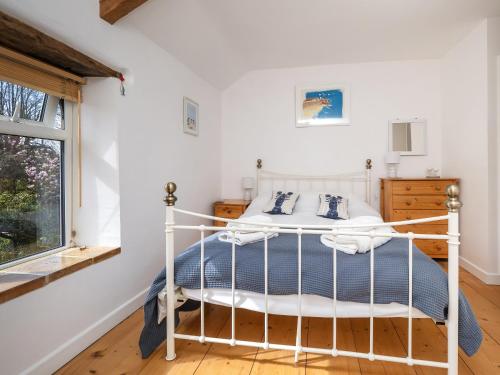 a bedroom with a white bed and a window at Primrose Cottage in Aylmerton