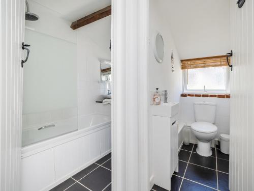 a bathroom with a toilet and a tub and a sink at Primrose Cottage in Aylmerton