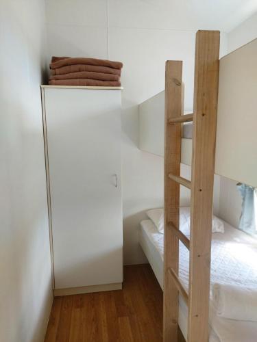 a small bedroom with a white refrigerator and a bunk bed at Stoney Park Holiday Park in Telegraph Point