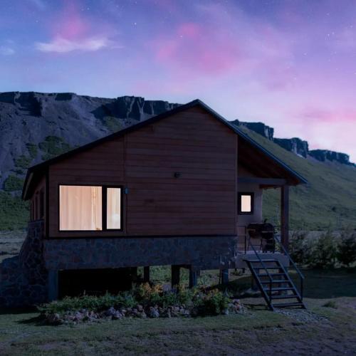 a cabin with a staircase in front of a mountain at PEWMA Casa de Montaña in Caviahue