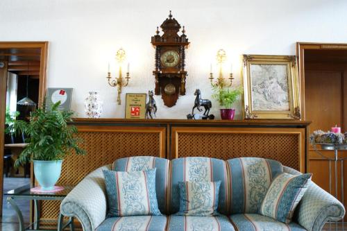 a living room with a couch and a clock on the wall at Heidehotel Herrenbrücke in Faßberg