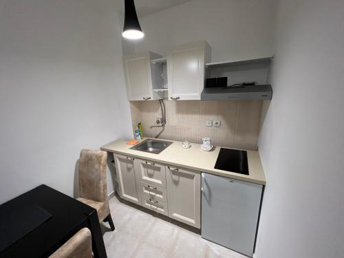 a small kitchen with white cabinets and a sink at Apartman Castor in Vrnjačka Banja