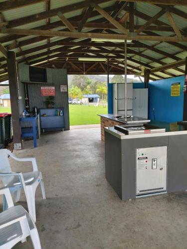 a kitchen with a stove and chairs in a pavilion at Stoney Park Holiday Park in Telegraph Point