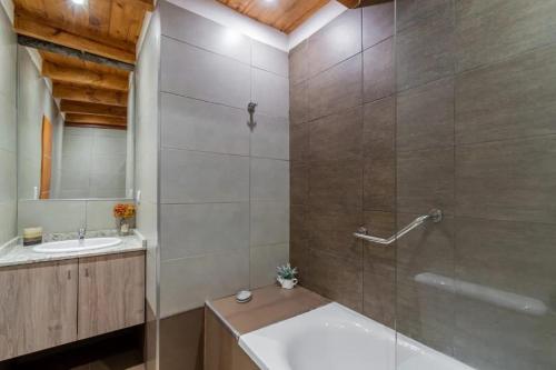 y baño con ducha, bañera y lavamanos. en PEWMA Casa de Montaña en Caviahue