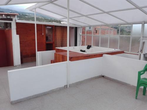 a white room with a tub and a green chair at Posada Turística Estancia Real in Sutamarchán
