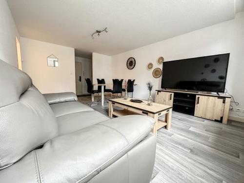 a living room with a couch and a flat screen tv at Résidence Bury in Tulle
