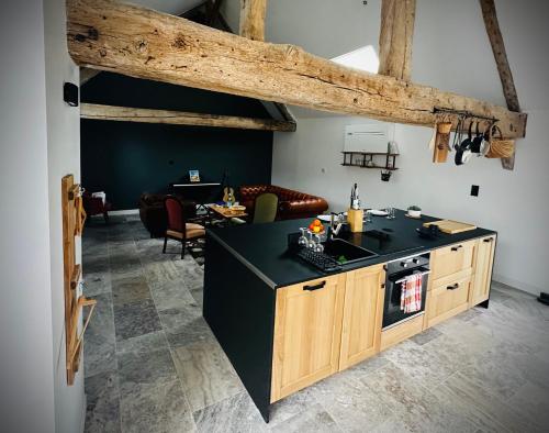 eine Küche mit einer schwarzen Arbeitsplatte und ein Wohnzimmer in der Unterkunft La vie en Grange, la Loire et les châteaux in Dhuizon