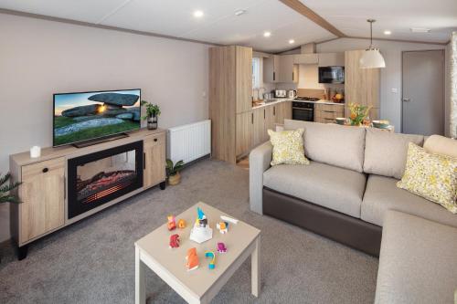 a living room with a couch and a tv and a table at Hawthorne Prestige Holiday Home in Chapel Saint Leonards