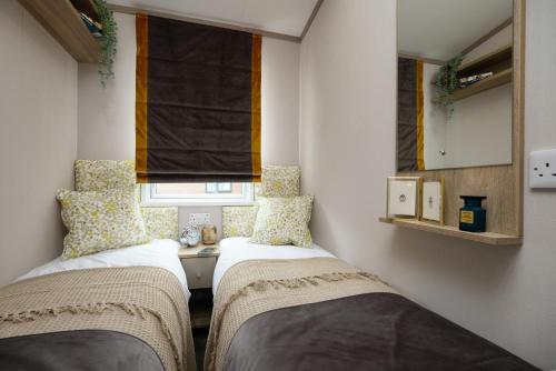 two beds in a small room with a window at Hawthorne Prestige Holiday Home in Chapel Saint Leonards