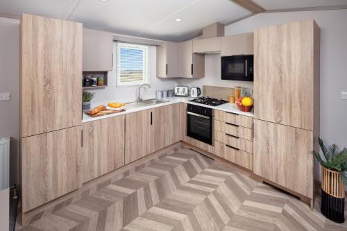 a kitchen with wooden cabinets and a wooden floor at Hawthorne Prestige Holiday Home in Chapel Saint Leonards