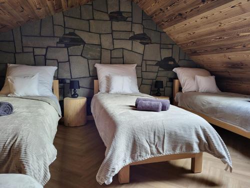 a bedroom with two beds and a stone wall at Apartamenty Stylo in Istebna