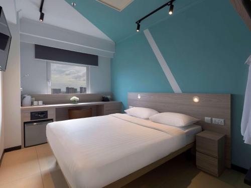 a bedroom with a white bed and a blue wall at ibis budget Phnom Penh Riverside in Phnom Penh