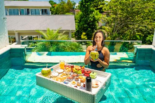 a woman sitting in a swimming pool with a drink at Pousada Apple House Paraty in Paraty