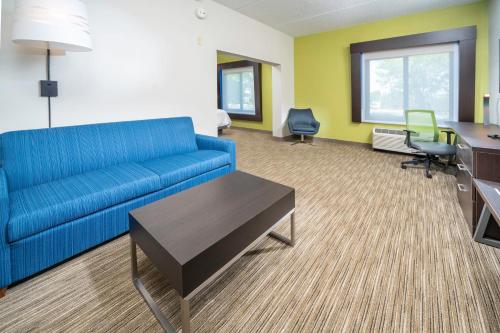 a living room with a blue couch and a desk at Holiday Inn Express Clayton Southeast Raleigh by IHG in Garner