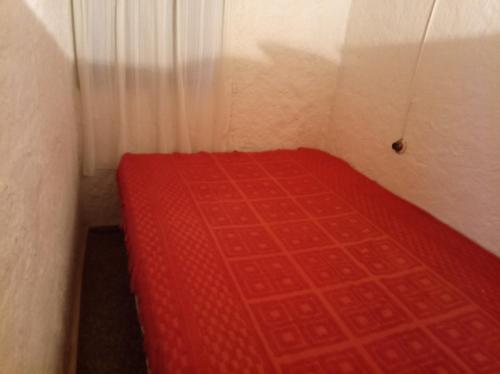 1 cama roja pequeña en una habitación pequeña en Gracias a Dios, en Aguas Dulces