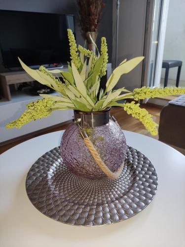a purple vase with a plant in it on a table at Nota Home in Novi Sad