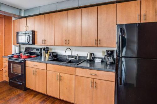 a kitchen with wooden cabinets and a black refrigerator at Centric Modern Loft w/ King Beds & Smart GameTable in Rochester