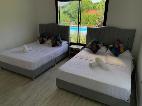 2 camas en una habitación con ventana en Acogedora cabaña, naturaleza, familia - NUEVA - ANAPOIMA en Anapoima