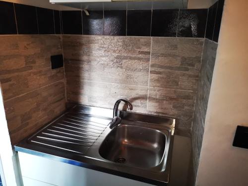 un fregadero de acero inoxidable en una cocina con azulejos negros en Kintsugi Loft en Turín