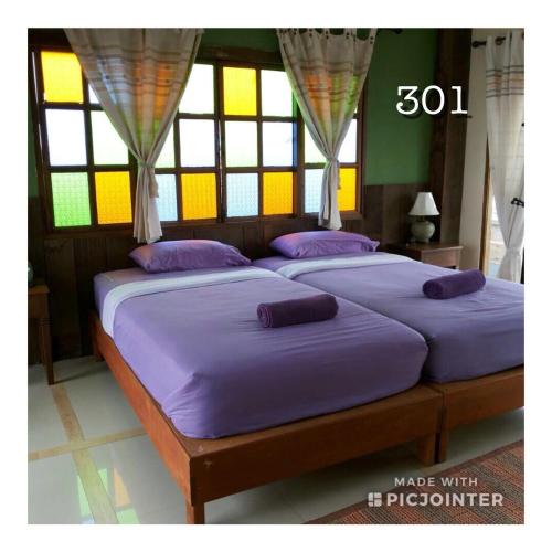 Cette chambre comprend 2 lits avec des draps violets et des fenêtres. dans l'établissement เชียงคานบุรี, à Chiang Khan