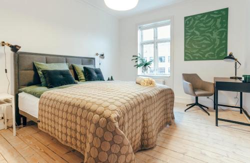Elegant, evocative and cosy home in Østerbro with a panoramic view. Eco-friendly. 1km harbour/ beach, 3km- city center, 13km-airport. في كوبنهاغن: غرفة نوم بسرير كبير مع مكتب وكرسي