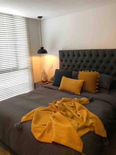 Un dormitorio con una cama con una manta amarilla. en EXCLUSIVO APARTAMENTO BOGOTÁ, en Bogotá