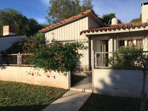 una casa con una puerta y un arbusto con flores rojas en CASA - CHALET VILLA DEL DIQUE en Villa del Dique