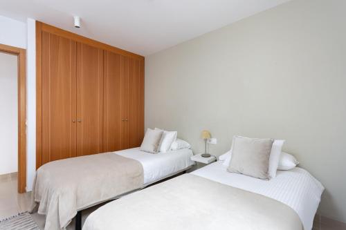 2 camas en una habitación con paredes blancas y armarios de madera en Céntrico y con Vistas Santa Cruz, Vacation Home, en Santa Cruz de Tenerife