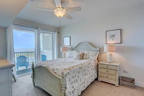 a bedroom with a bed with a ceiling fan and a window at TSC203 Fisher Oceanfront Elevator in Kill Devil Hills