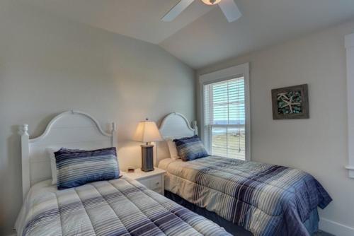 a bedroom with two beds and a window at TSC404 Seaclusion Oceanfront Elevator in Kill Devil Hills