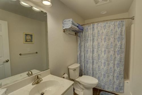 a bathroom with a toilet and a sink and a mirror at TSC404 Seaclusion Oceanfront Elevator in Kill Devil Hills