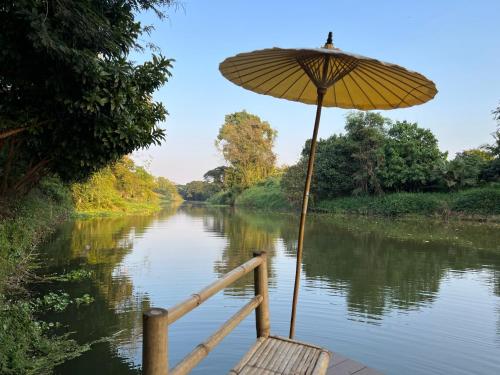 a chair with an umbrella next to a river at Home of Dusita in Lamphun