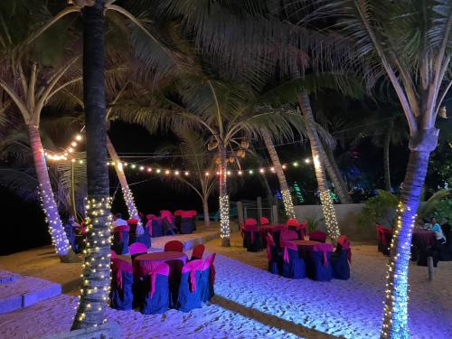 a beach wedding on the sand with palm trees and pink chairs at Aprima Hotel in Kalutara