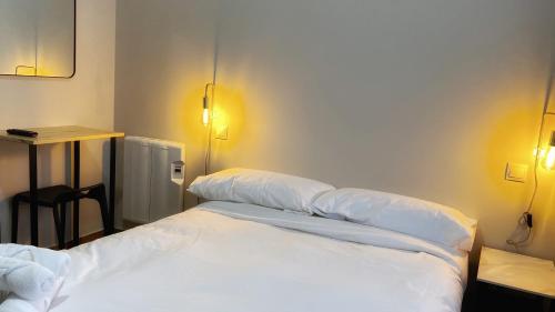 Iturriaga Ostatua Self check in في بلباو: سرير أبيض في غرفة مع وسادتين