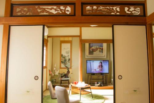 a living room with sliding glass doors and a tv at 幽舍の庭 in Izumi-Sano