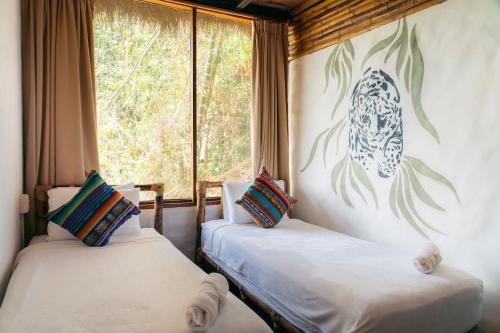 two beds in a room with a window at Cotococha Amazon River Lodge in Tena