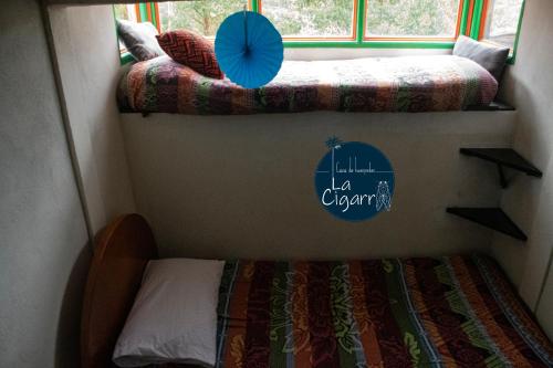a small room with two beds and a window at La Cigarra Casa de Huéspedes in Salento