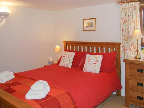 a bedroom with a red bed with two towels on it at Blencathra in Mungrisdale