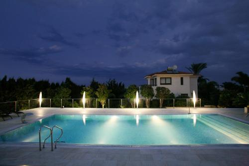 a swimming pool at night with a house in the background at Villa Leonidas in Protaras