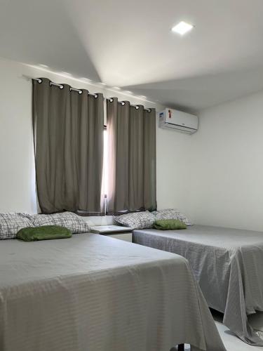 a room with two beds and a window with curtains at Casa da Praia Carapibus in Conde